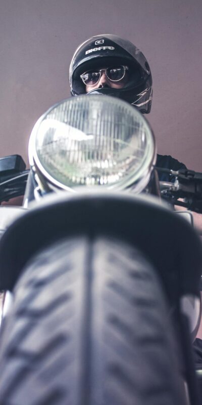 A vintage motorcycle rider in Varanasi, India wearing a helmet and sunglasses.