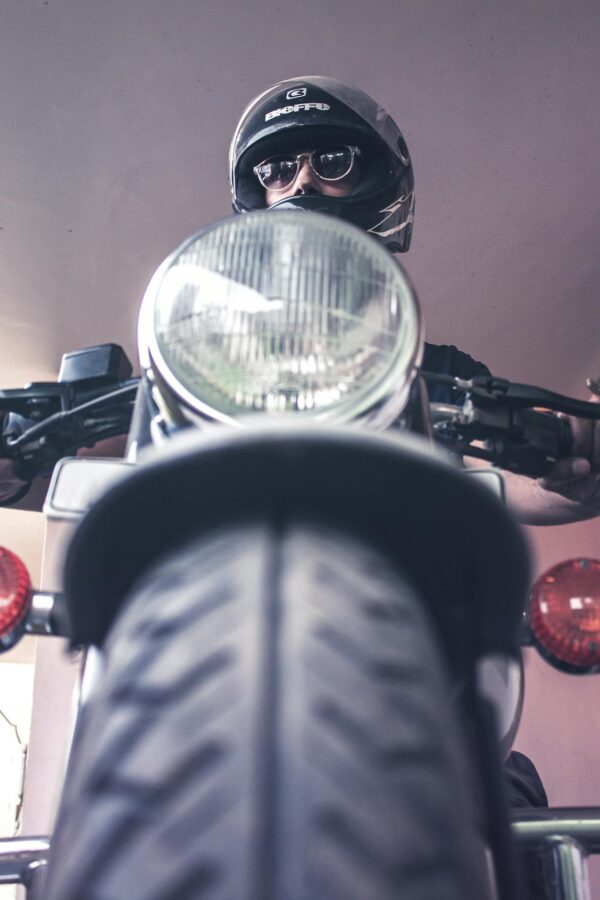 A vintage motorcycle rider in Varanasi, India wearing a helmet and sunglasses.