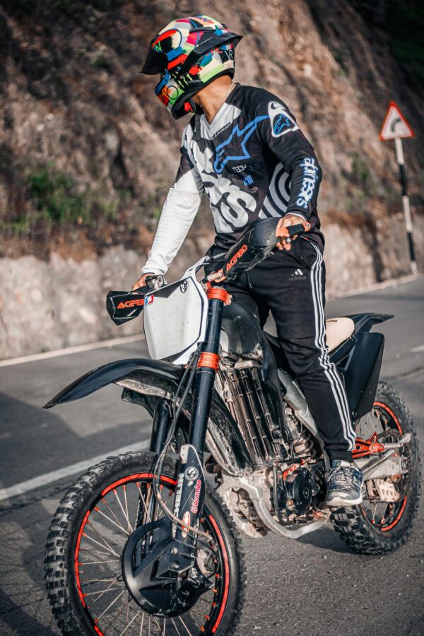 Biker in full gear rides a motorcycle on a curved mountain road, dressed for high-speed adventure.